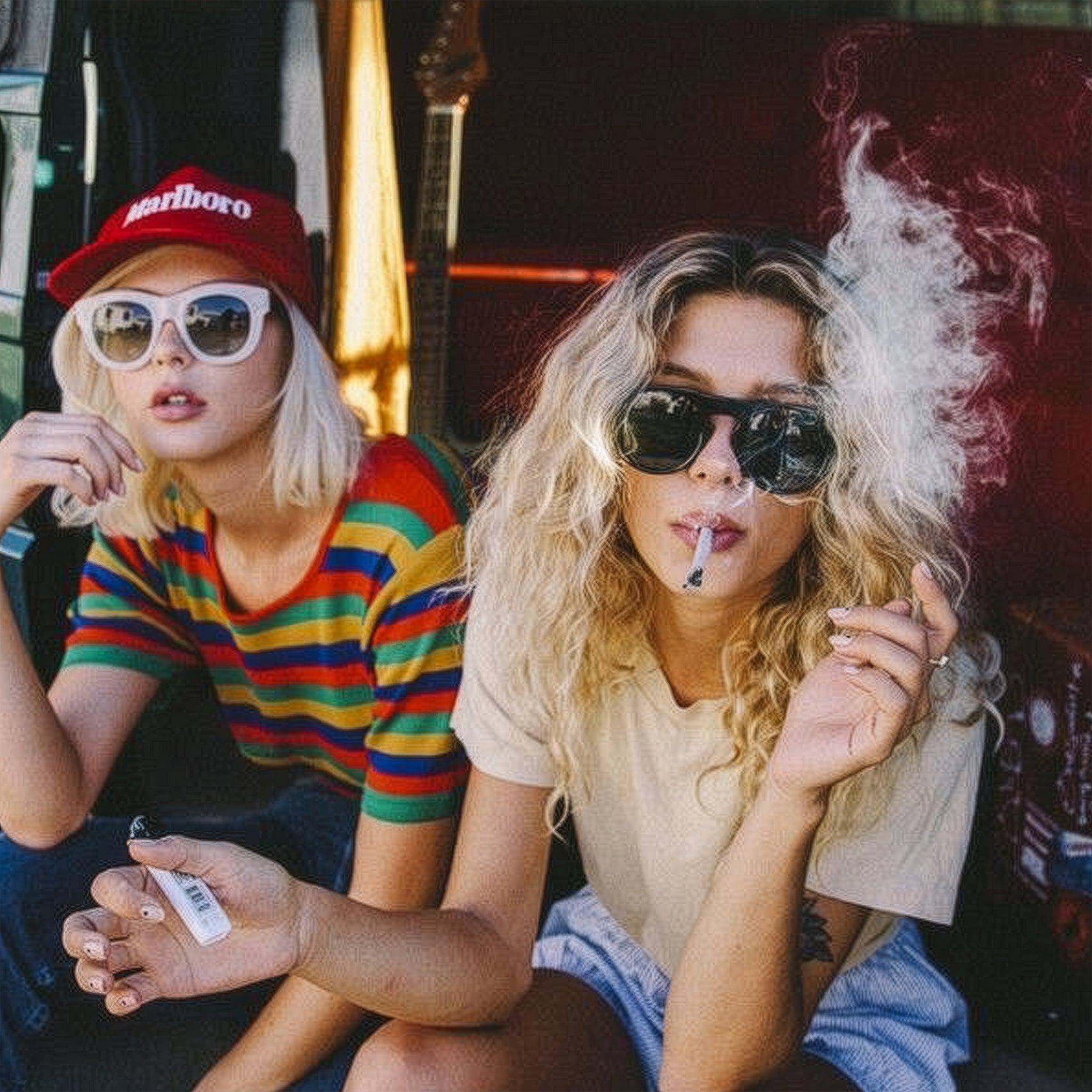 Two people sitting together, one smoking a joint, in a casual setting.
