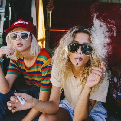 Two people sitting together, one smoking a joint, in a casual setting.